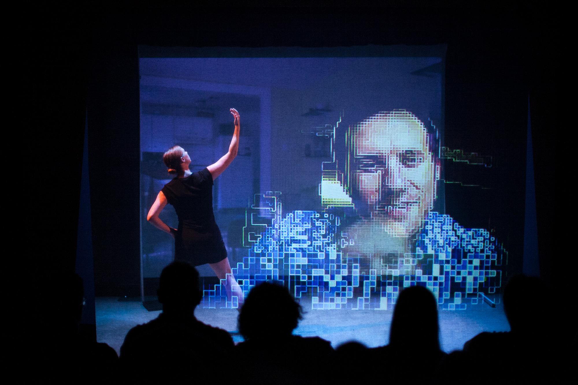 man's face projected on screen and woman in front