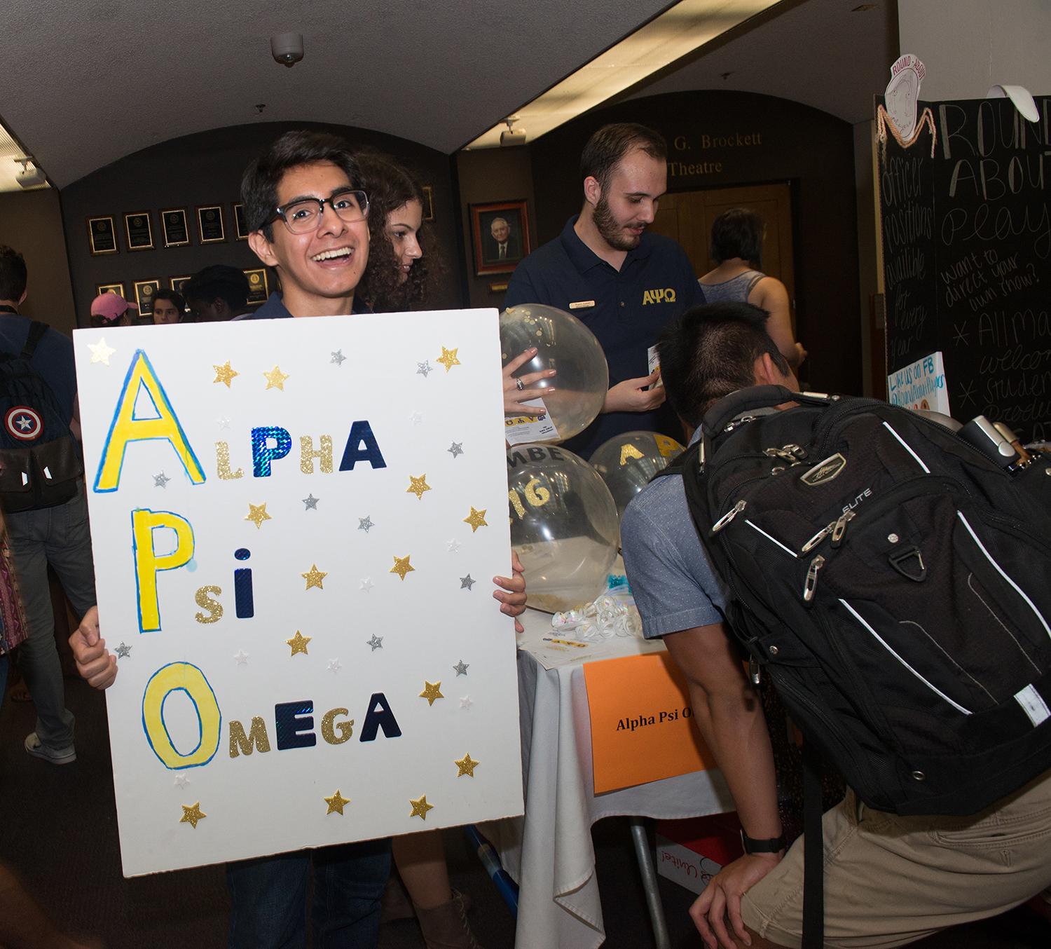 man holding an alpha psi omega sign