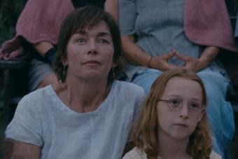 A still from Annie Baker's film JANET PLANET, featuring a mother and daughter sitting in a crowd