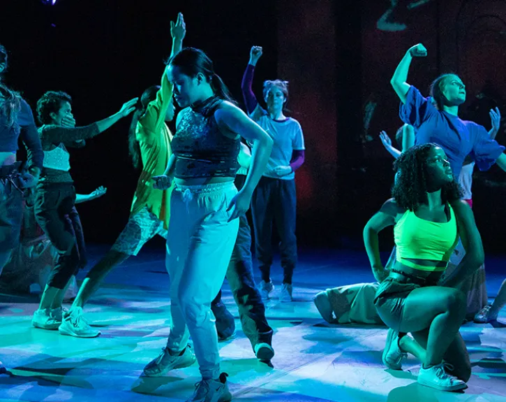 dancers standing in group illuminated in blue
