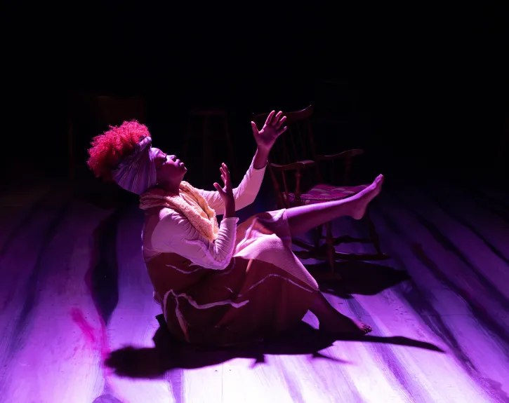 actress looking and reaching up to the ceiling, washed in purple light