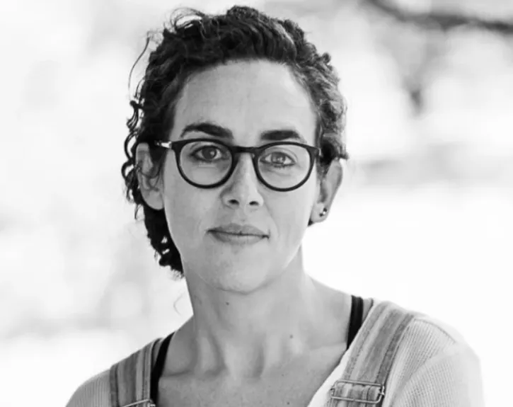 A woman with dark curly hair wearing glasses