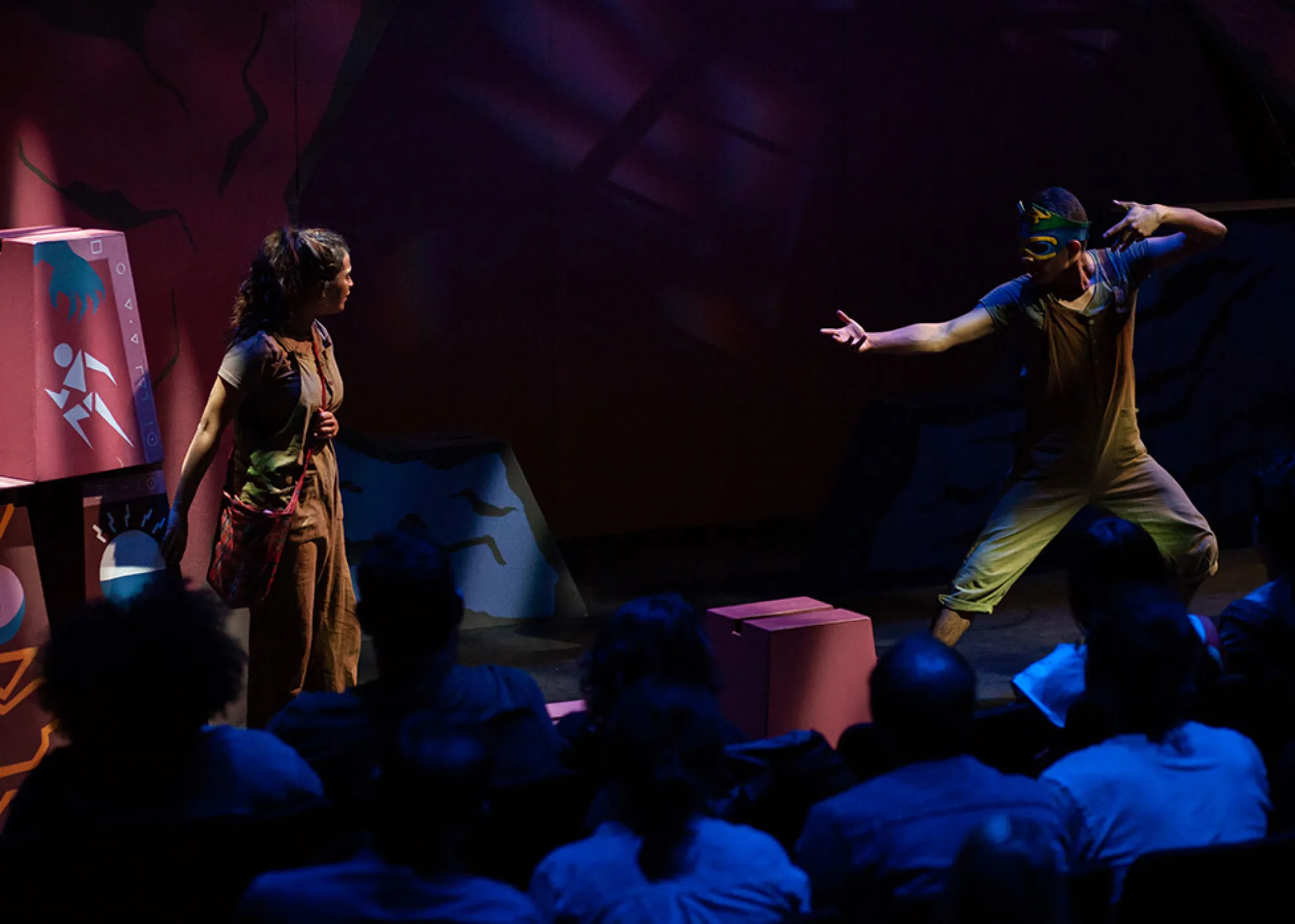 an actor makes the motions of drawing a bow and arrow towards an actress that stands in front of him
