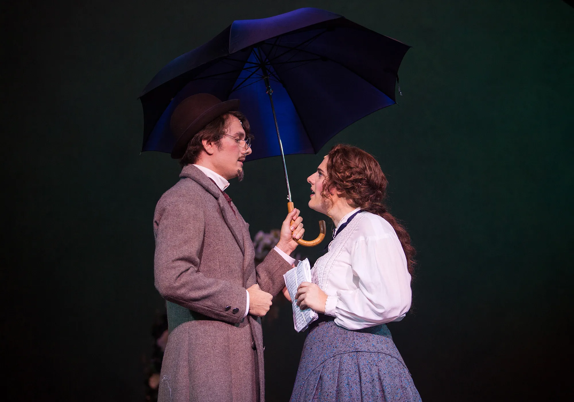 man holding umbrella while looking down at woman