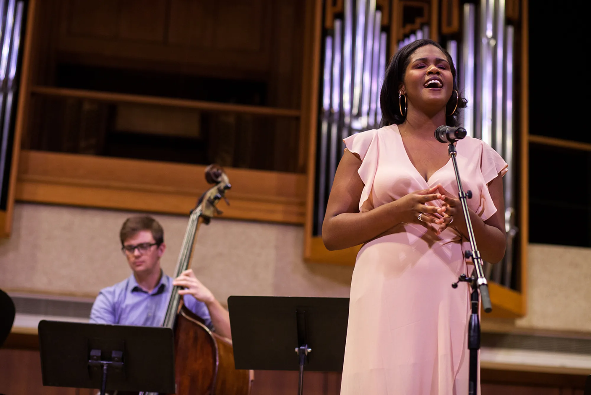 The Gospel According to Jocelyn; Photo: Lawrence Peart woman in pink sings while man in the back plays the cello