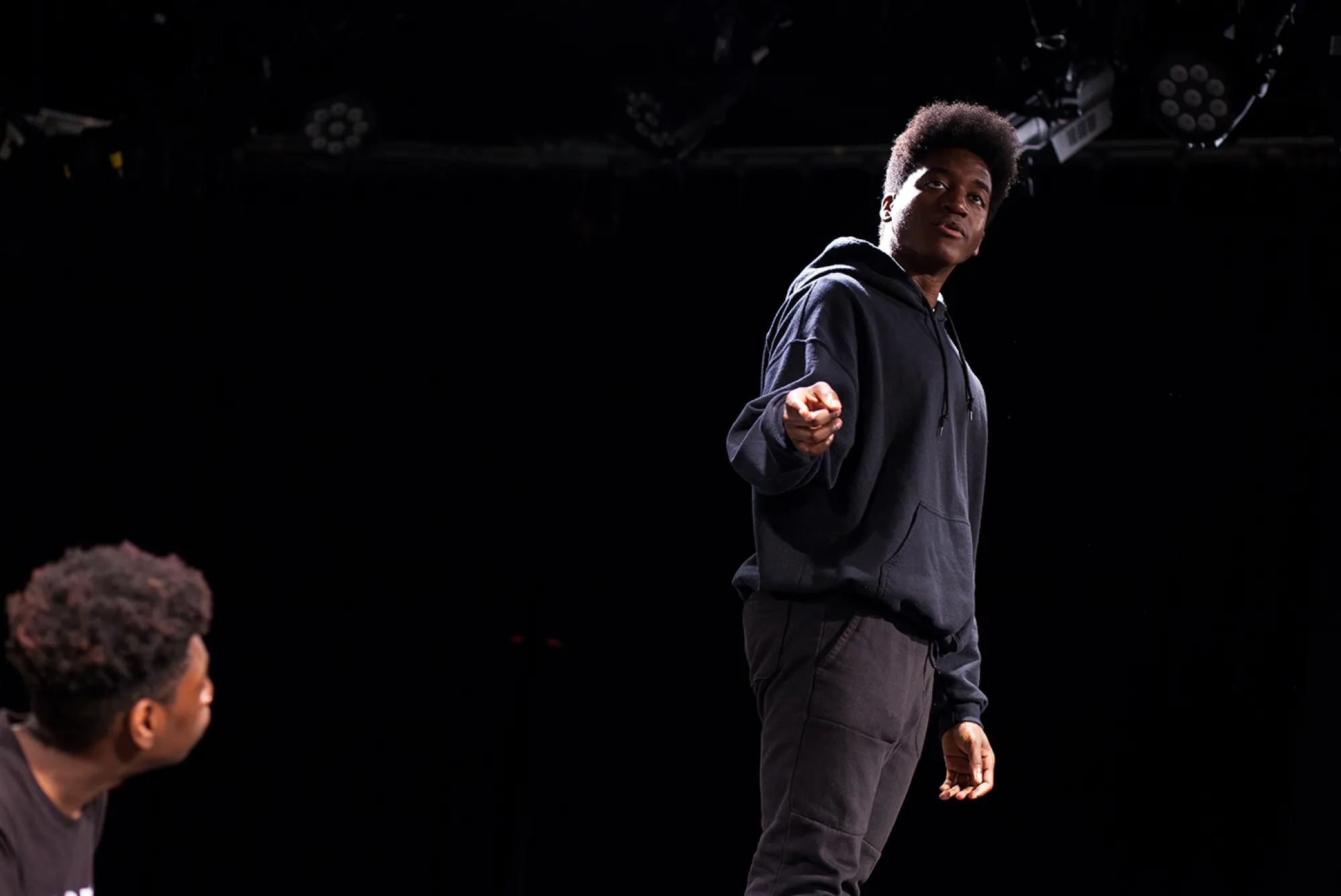 Rage to Heal; Photo: Lawrence Peart man stands in the dark pointing at another