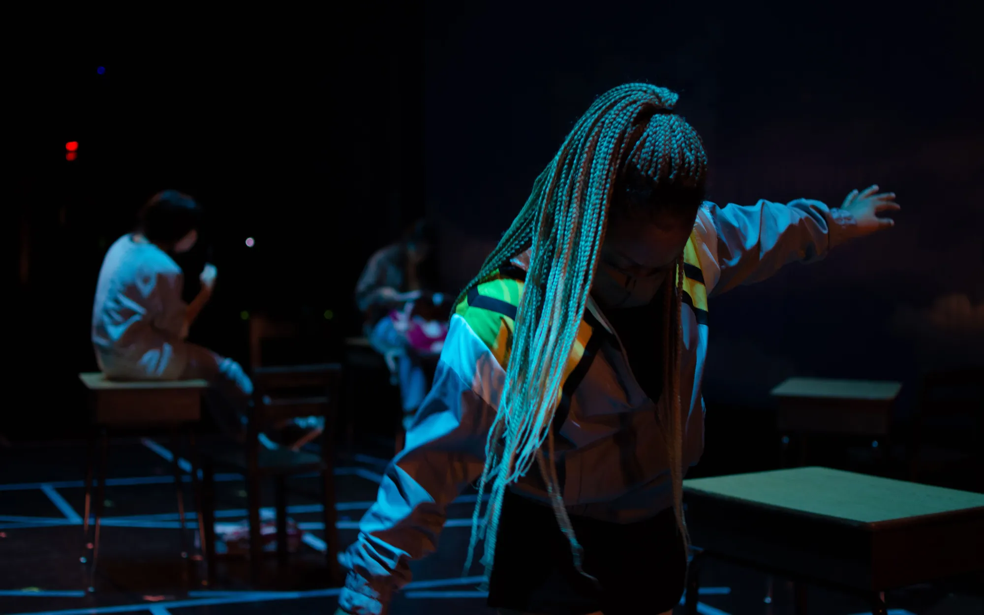actress with braided hair in a ponytail stretches her arms out, washed in blue light