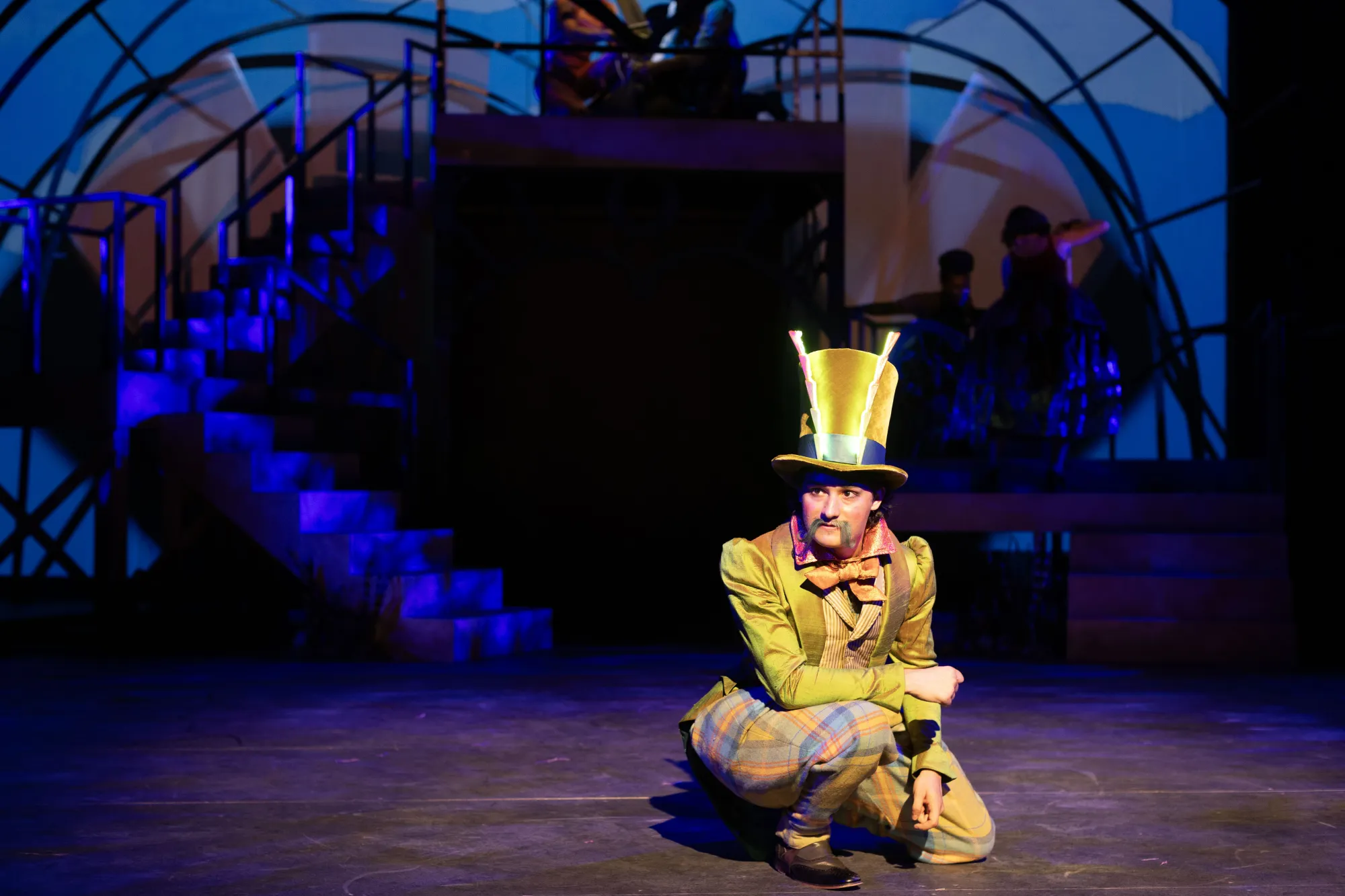 Letting the audience in on a secret, Grasshopper, played by Dominic Gross, leans down toward the edge of the stage