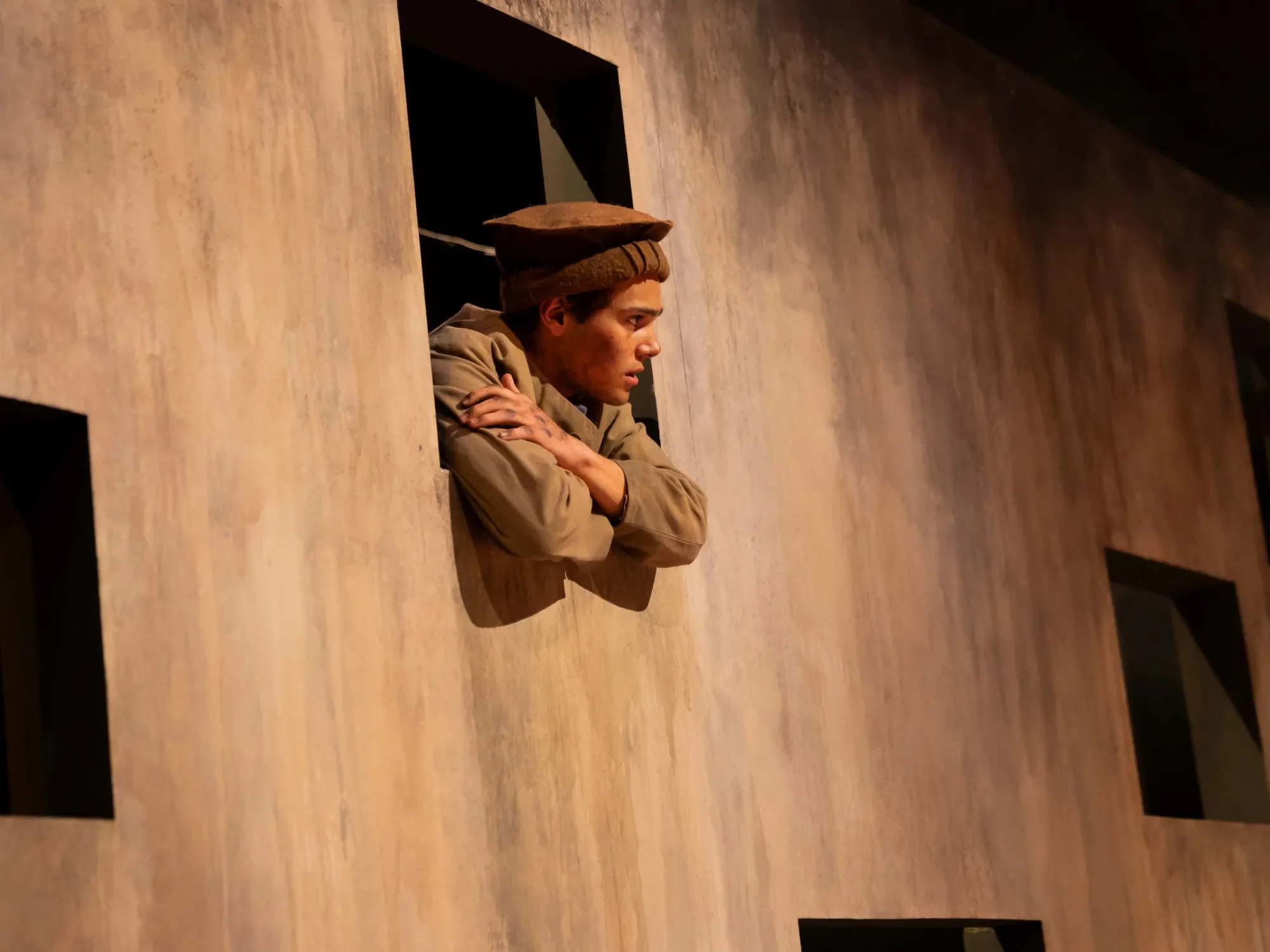 The Stable Boy played by David Gonima leans through a window he is not supposed to. He is talking while he should be working...