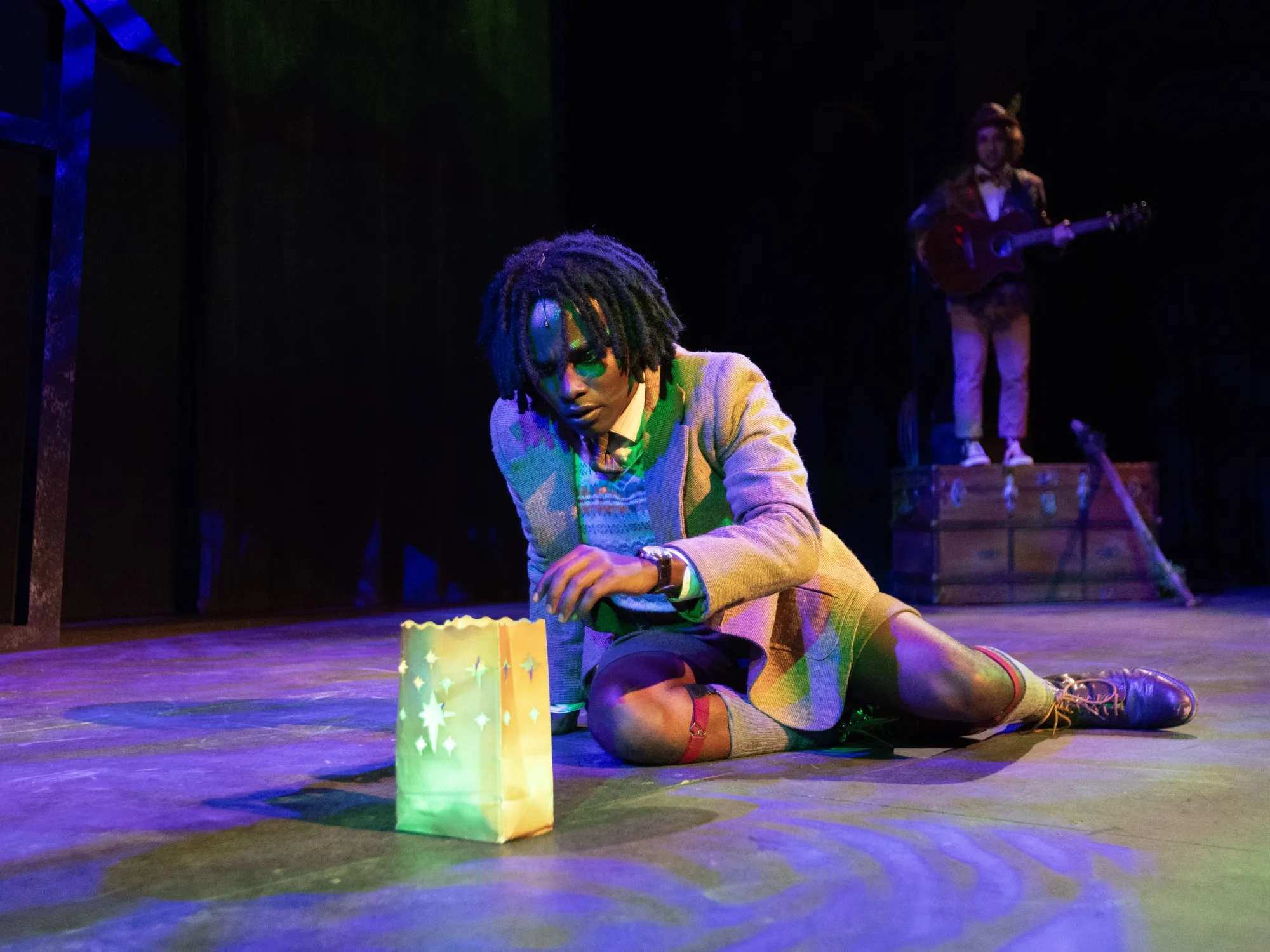 An actor performing in JAMES AND THE GIANT PEACH looks with curiosity at a glowing paper bag