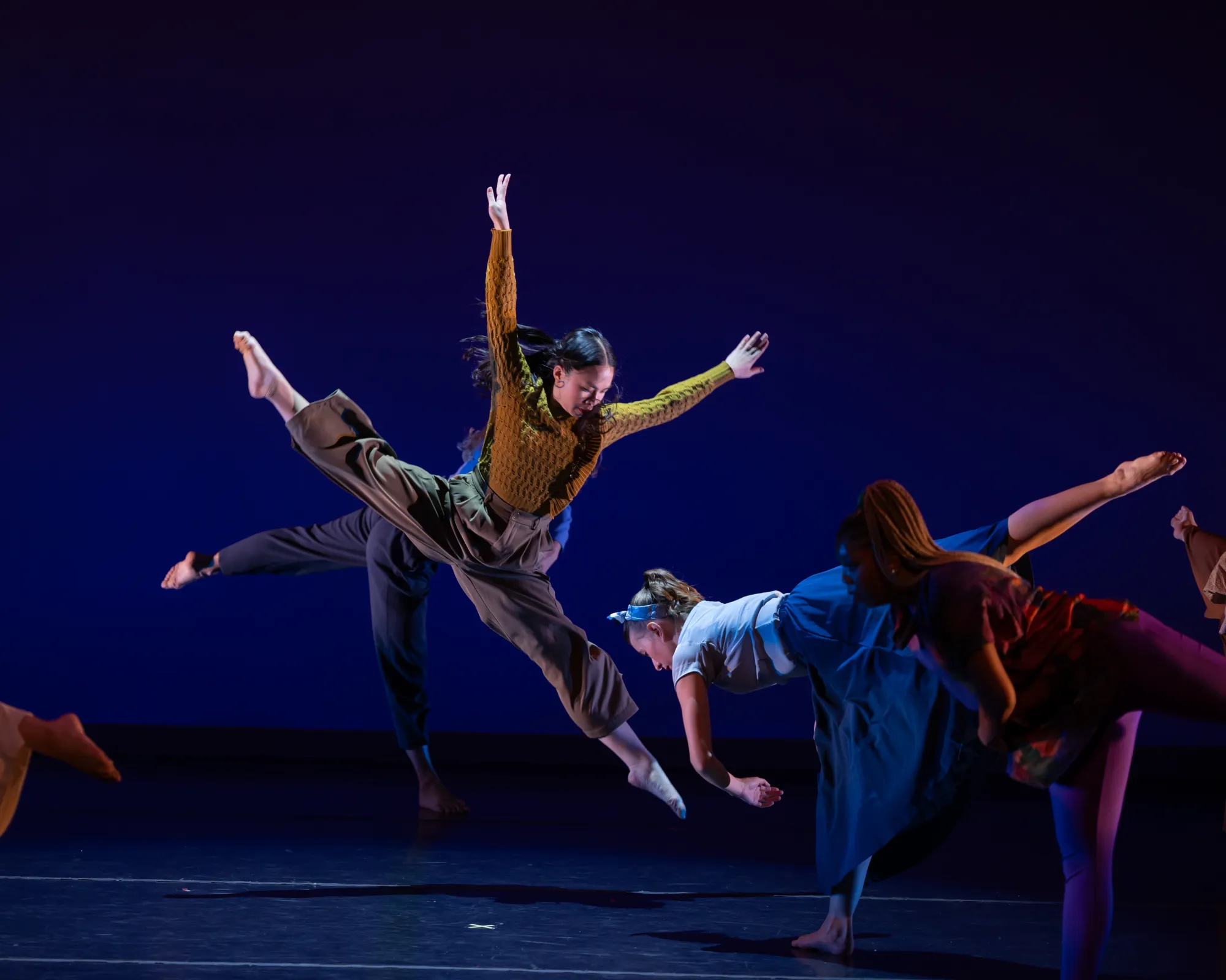 A dancer photographed mid-leap, their arms stretching upward