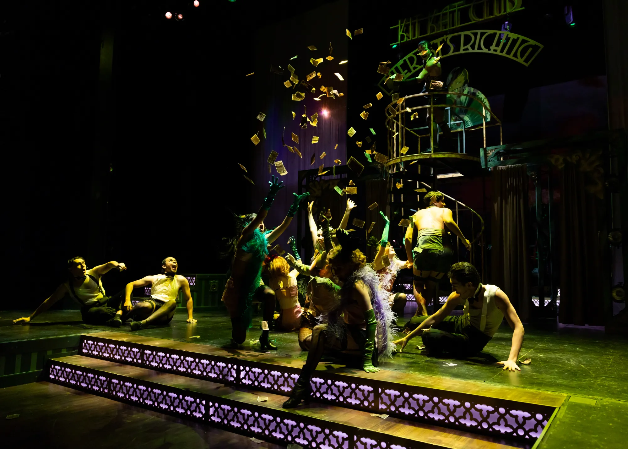 A crowd of dancers reaches for falling money