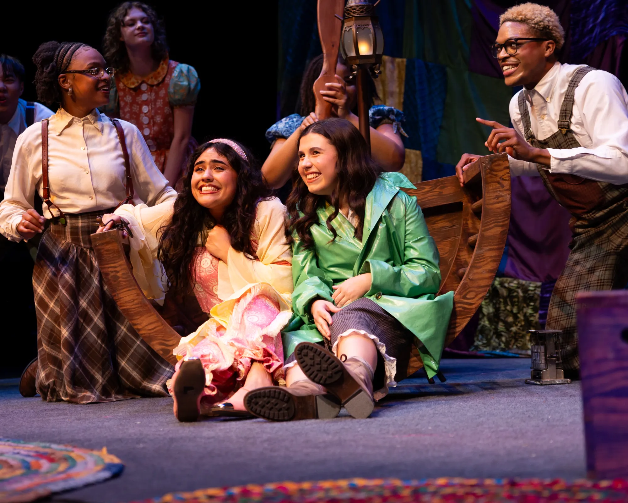 A girl in a pink dress sits next to a girl in a green raincoat