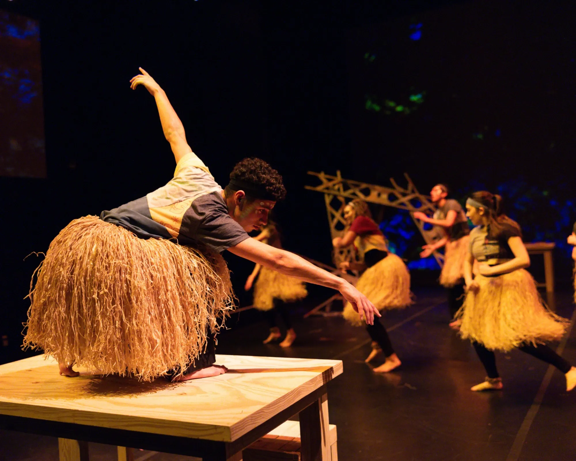 A dancer in a grass skirt extends his arms