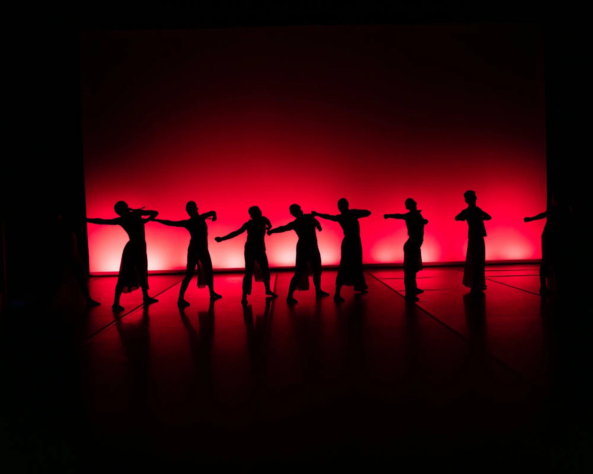 A line of silhouettes is illuminated by red light