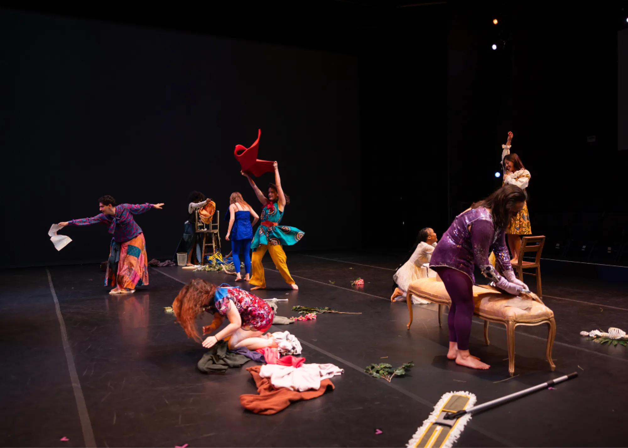 Dancers in colorful clothing play with an assortment of objects