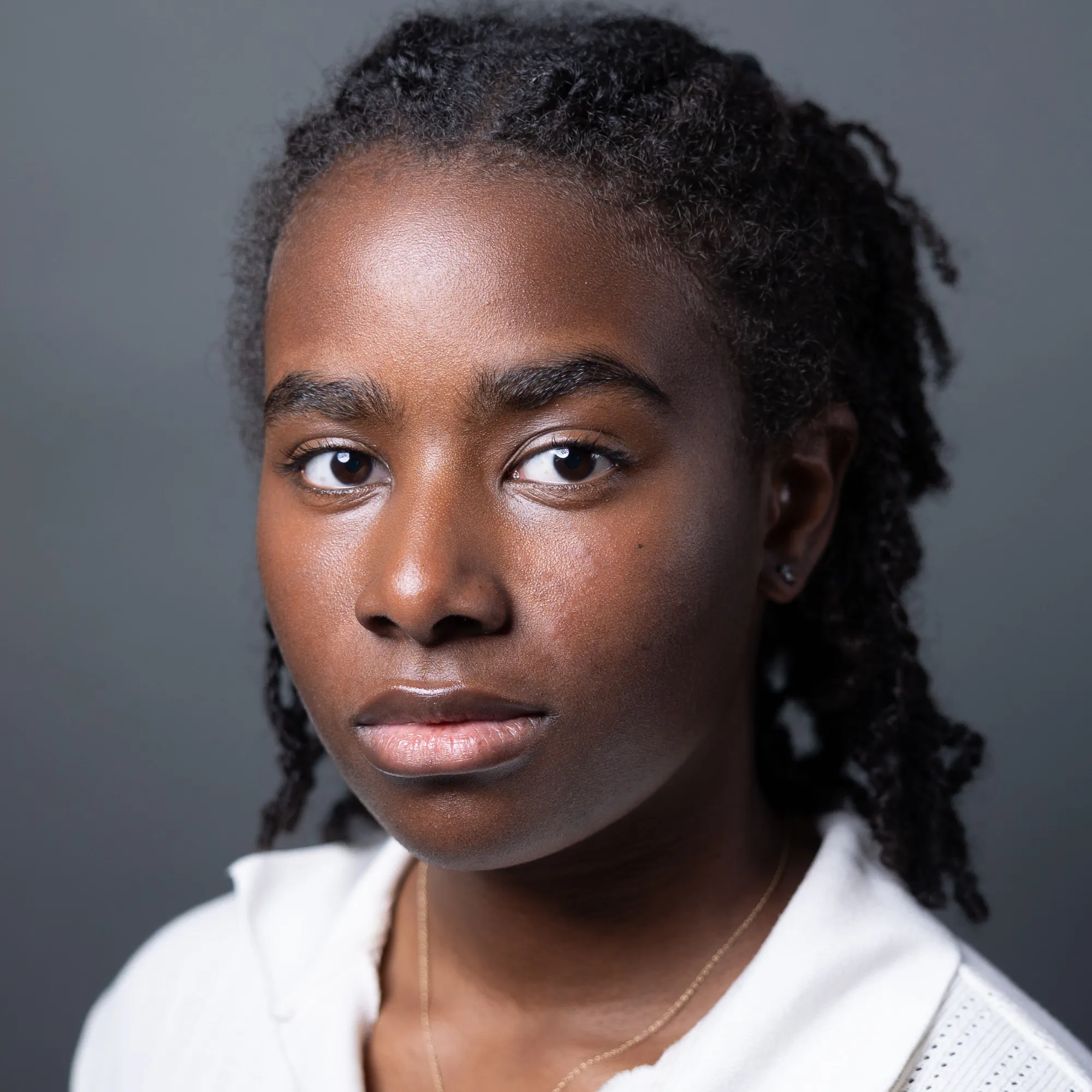 A woman with black braids wearing a white collared shirt