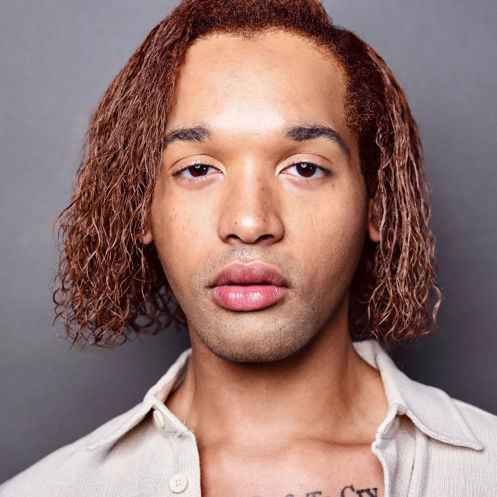 A man with red curly hair wearing a collared shirt