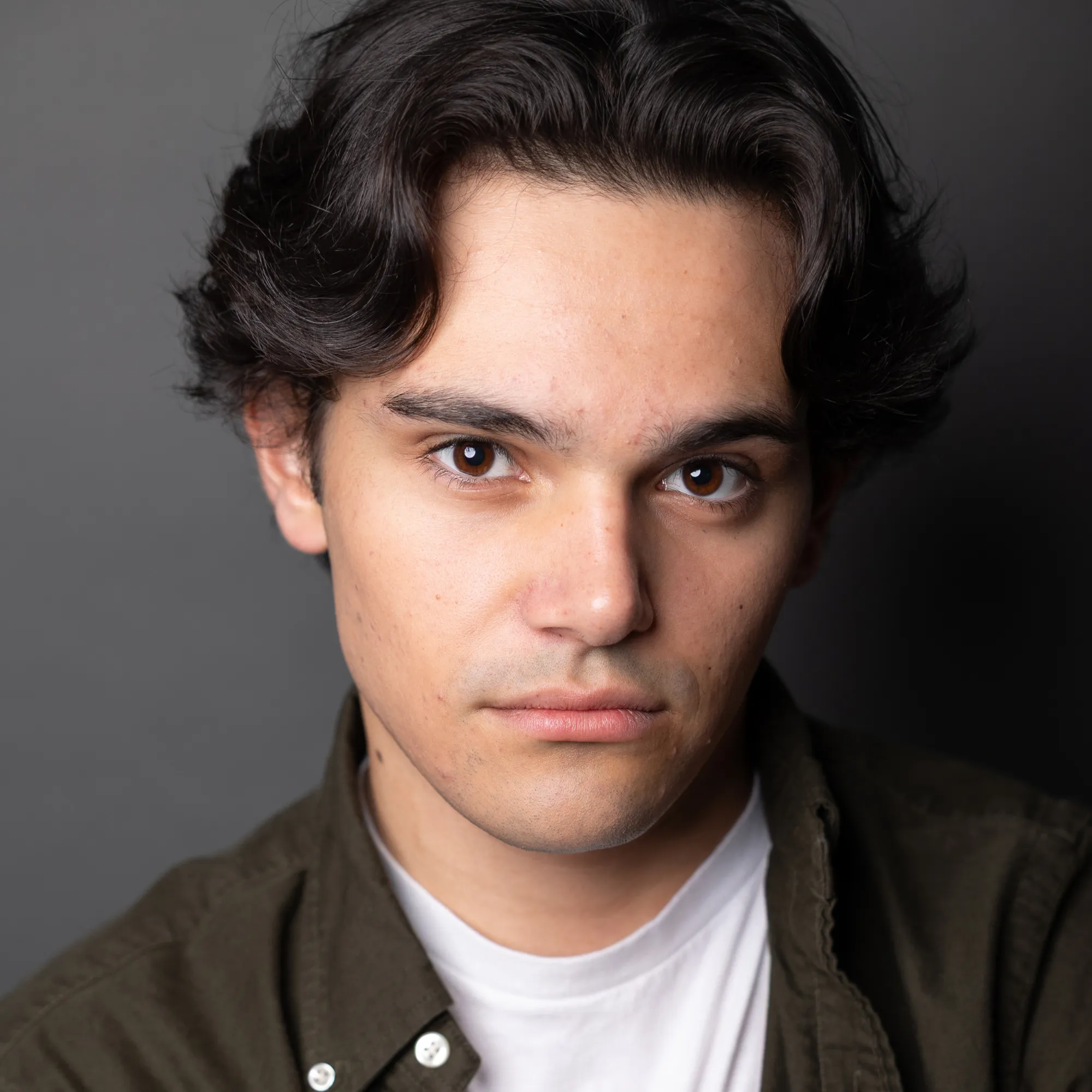 A man with short dark hair turns toward the camera