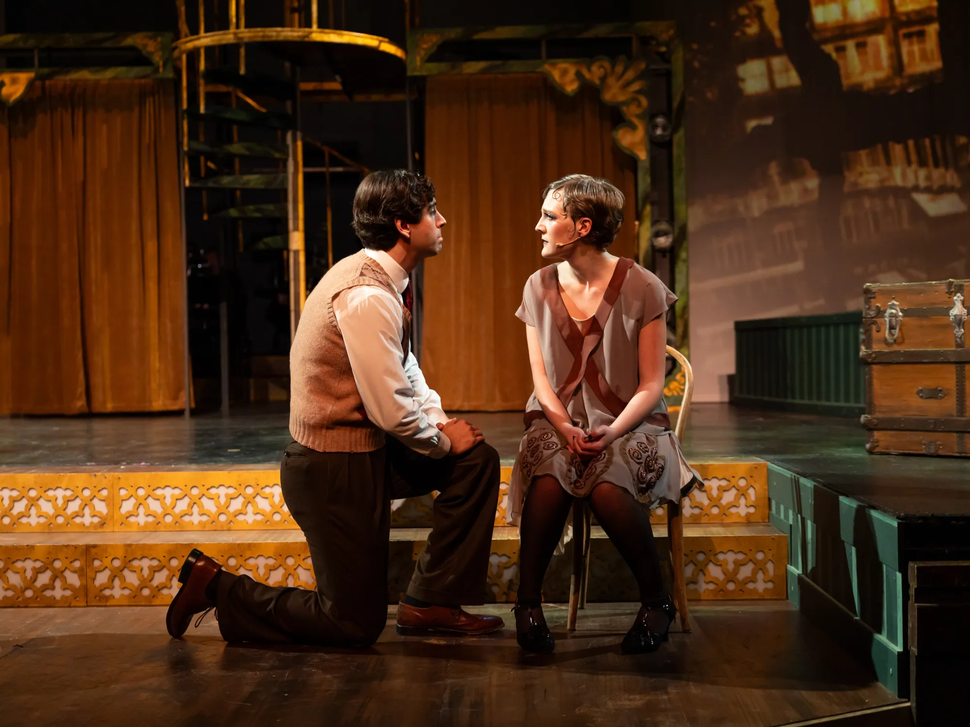 A man on one knee looks towards a woman sitting