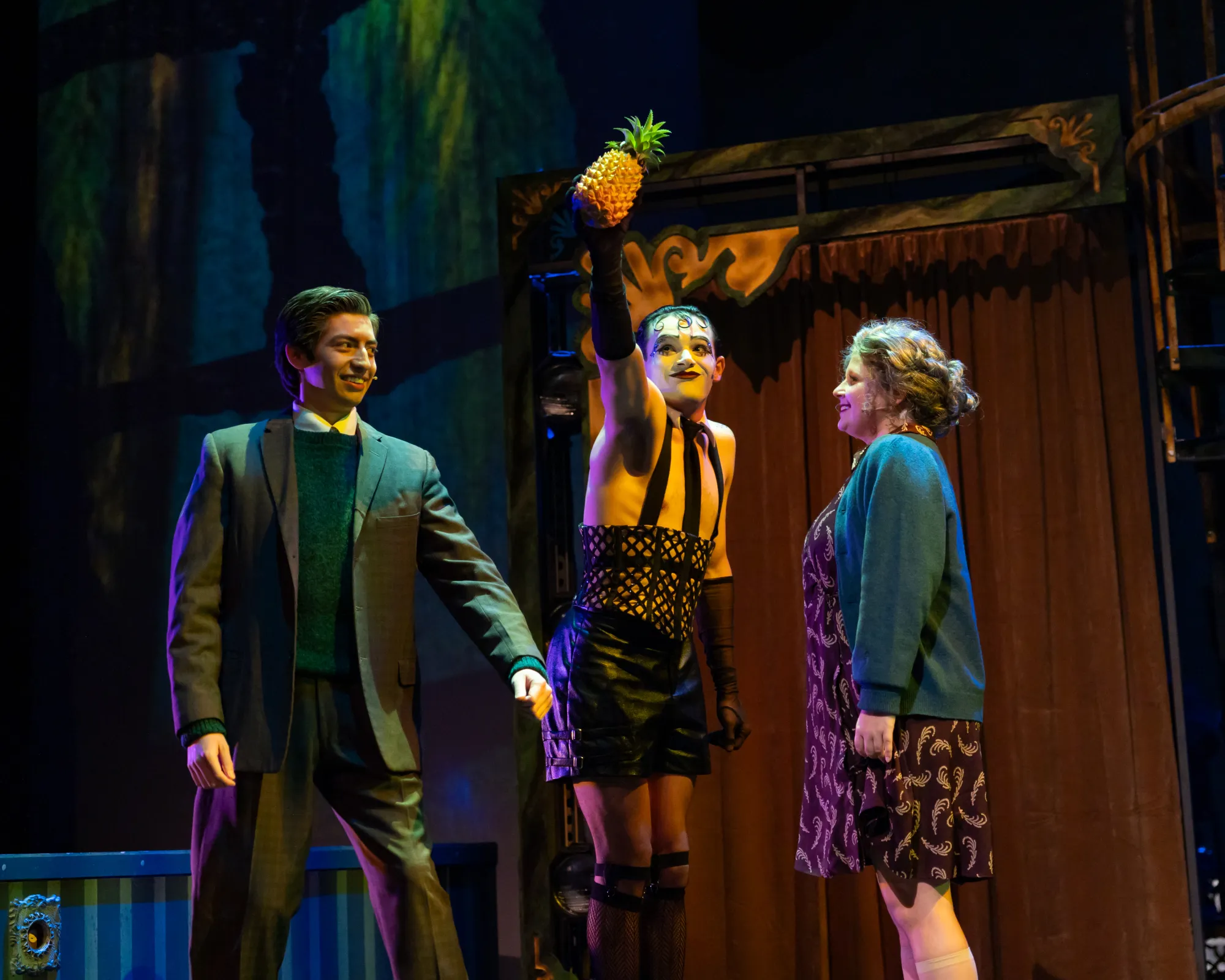 A man holds a pineapple between a couple