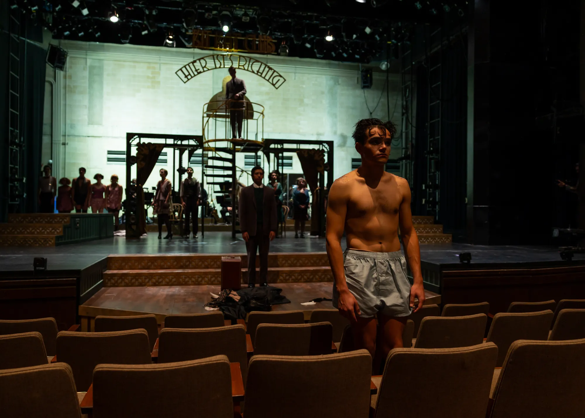 A man stands in the audience while the cast onstage looks forward
