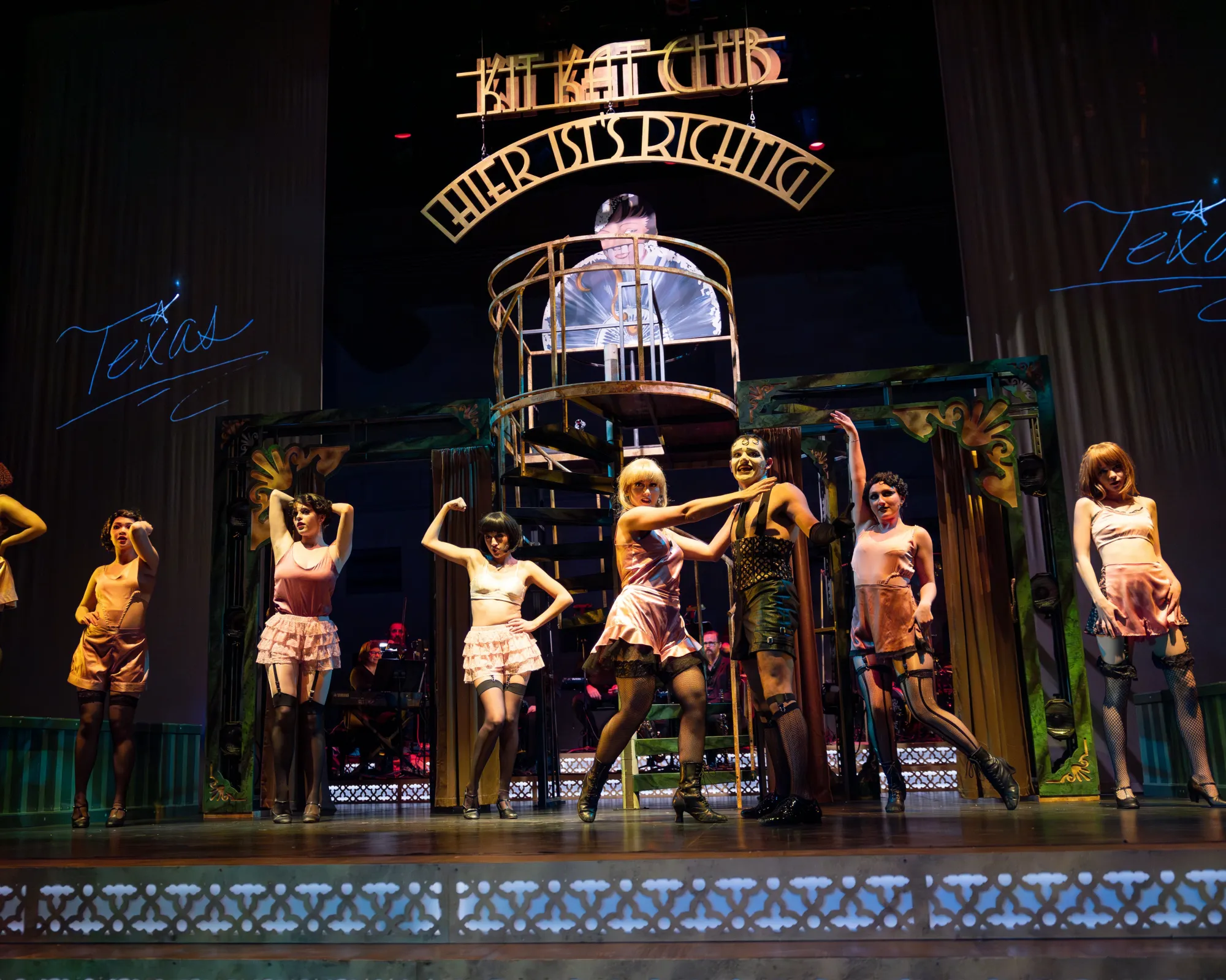 A man surrounded by a group of dancers wearing pink underwear