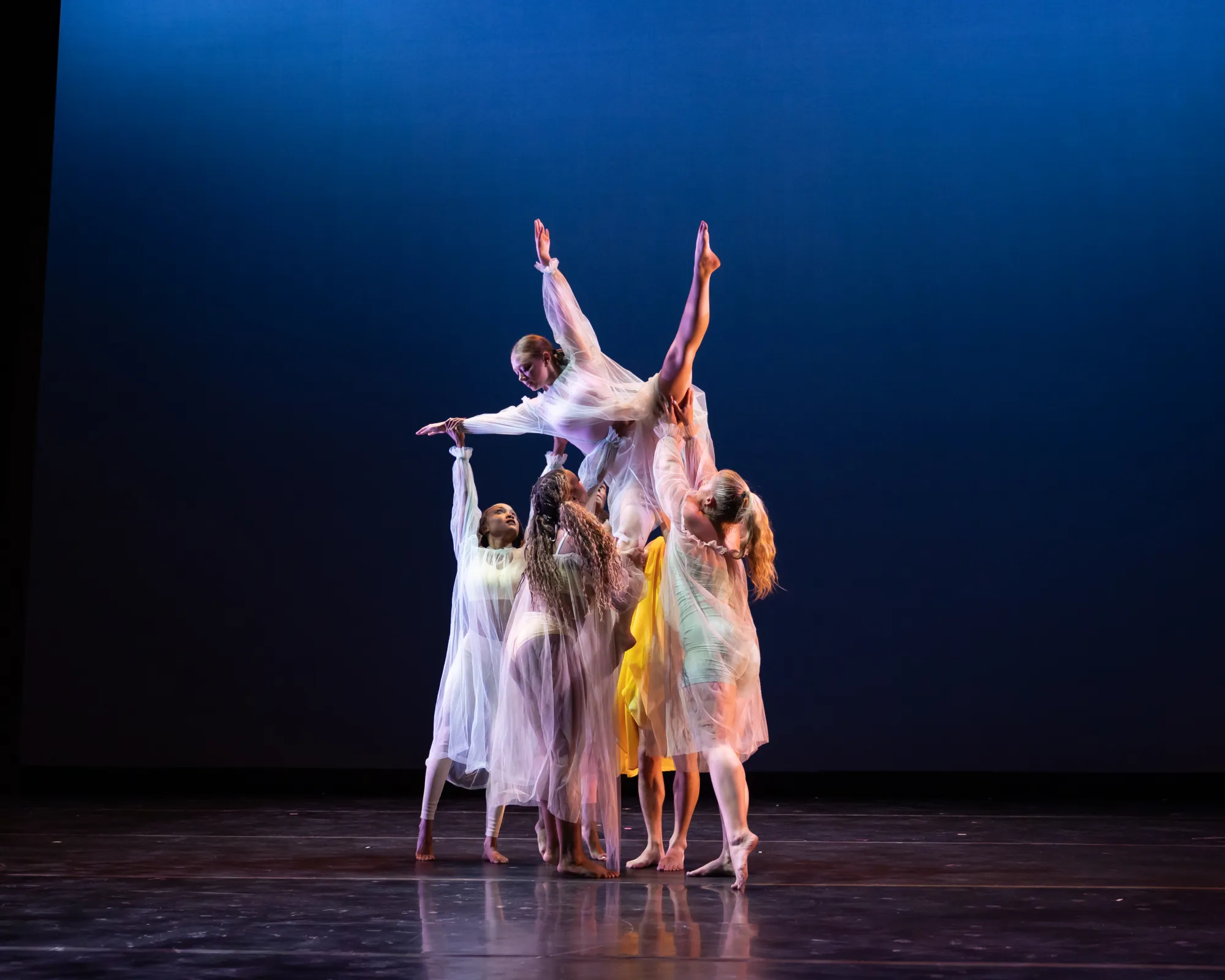 A group of dancers raises another dancer into the air