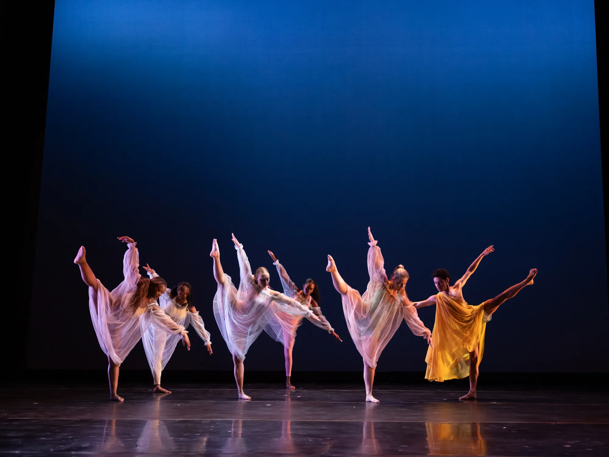 A group of dancers extends their leg upwards