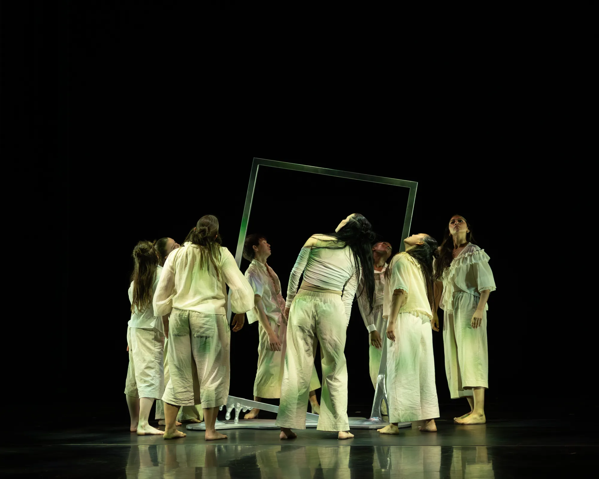 A group of dancers lean in front of an empty frame