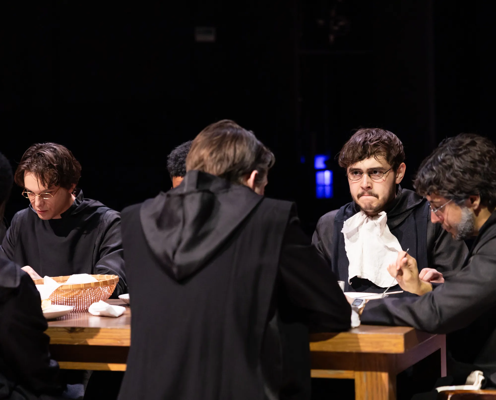 A monk looks grim while sitting at a dinner table