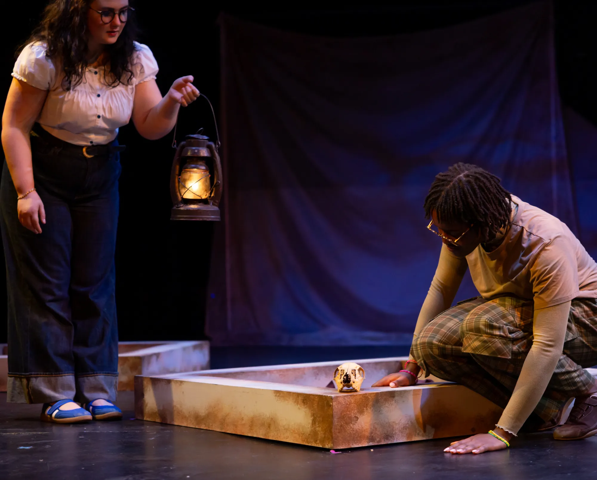 An actor uses a lamp to look at a rabbit skull