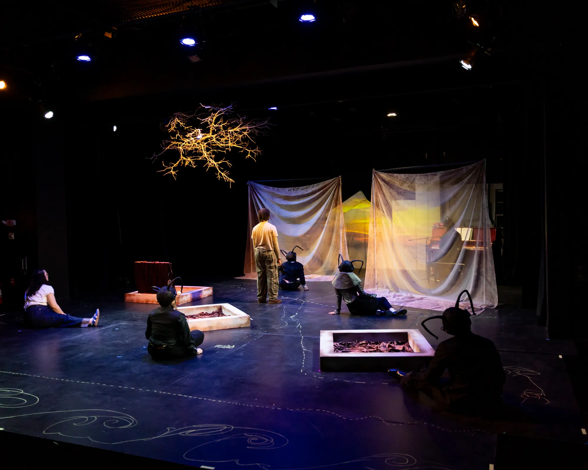 A group of actors face upstage