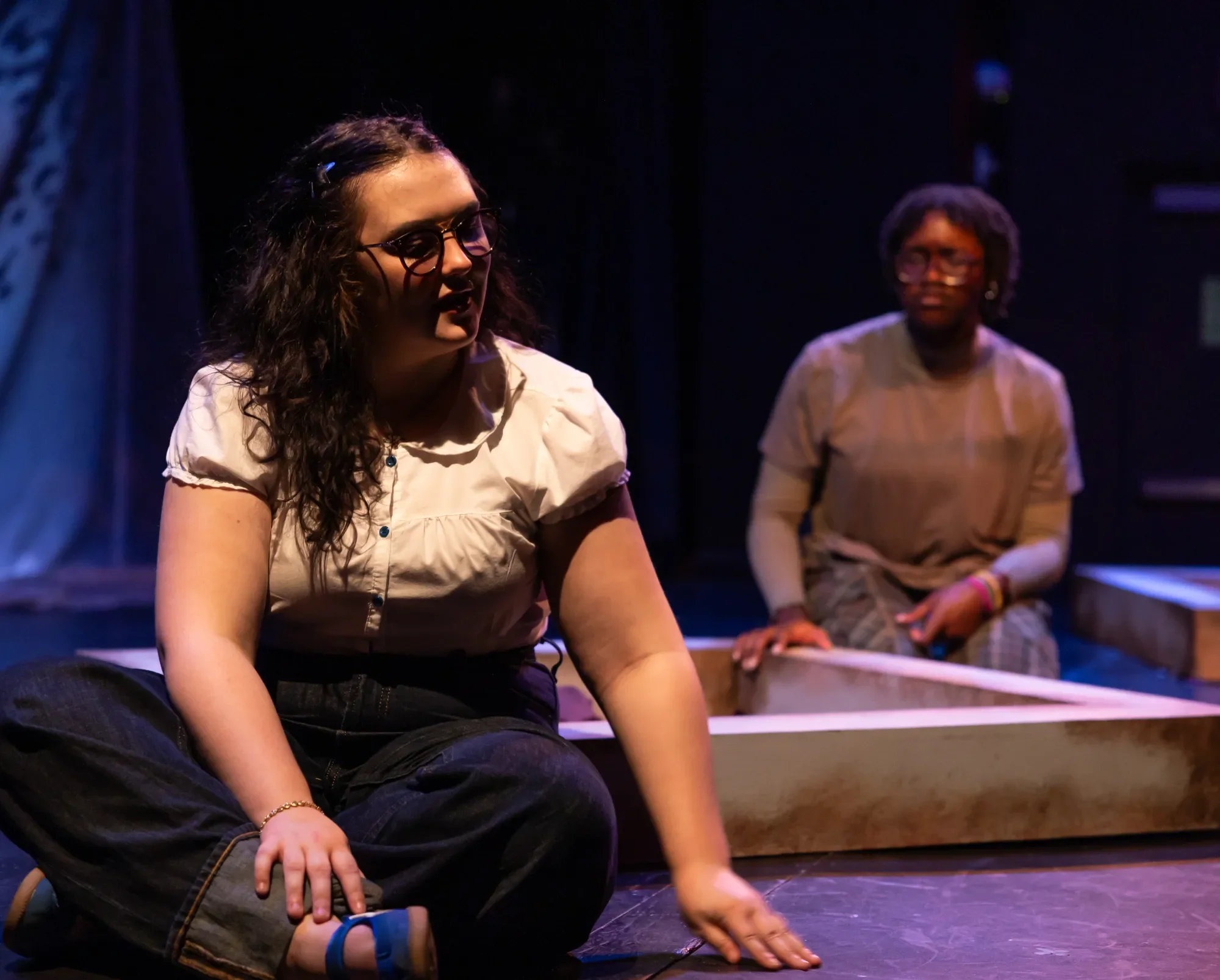 An actor in a white blouse turns to look behind her