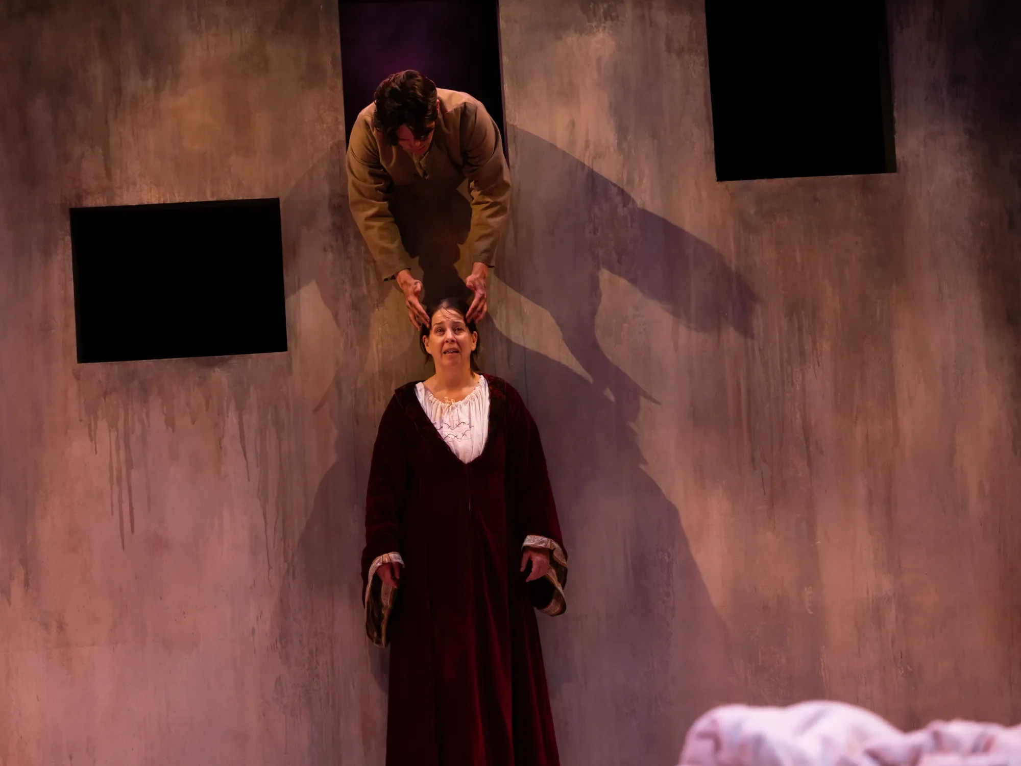 A boy leans through a window to rub a woman's temples