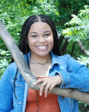 Photo of Stori Jasper in a jean jacket standing in a wooded area