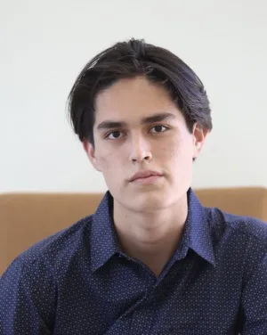 A man with black hair in a blue collared shirt