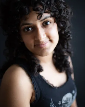 A woman with curly black hair in a black top
