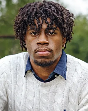 A man in a white sweater over a blue collared shirt