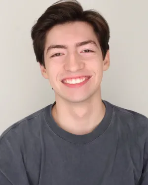 A man in a gray shirt smiles