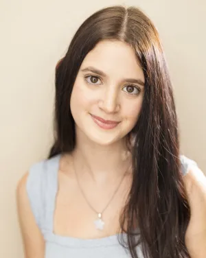 A woman with long brown hair smirks
