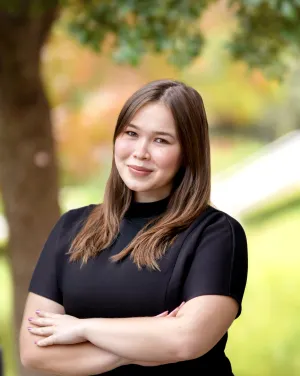 A woman in a black blouse crosses her arms over her chest