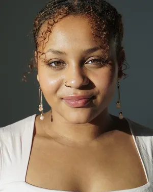 Photo of a woman in a white shirt and curly hair pulled back