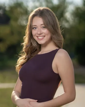 A woman in a maroon shirt and long blonde hair smiles
