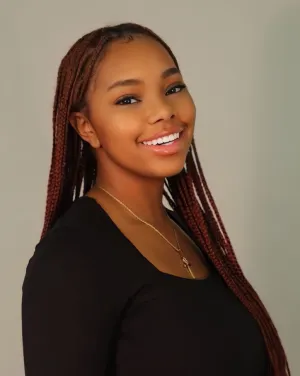 A woman with long braids turns and smiles