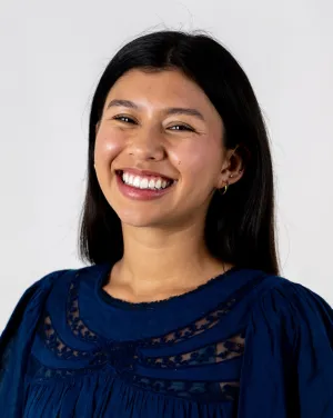A woman in a dark blue blouse smiles
