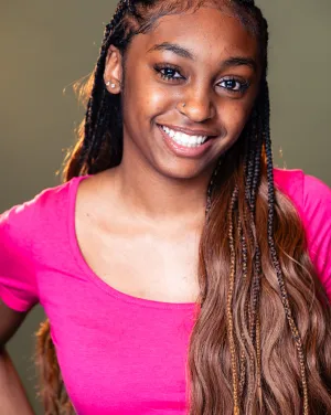 photo of a woman in a hot pink shirt smiling with long brown hair and braids