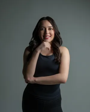 A woman in a black dress places her hand on her chin