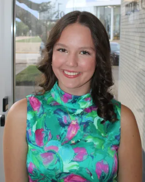 A woman in a green blouse smiles