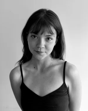 A black and white image of a woman with long black hair and bangs smiling